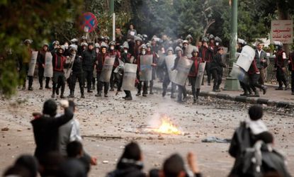 Protesters throw stones at riot police during clashes near Tahrir Square in Cairo on Jan. 28.