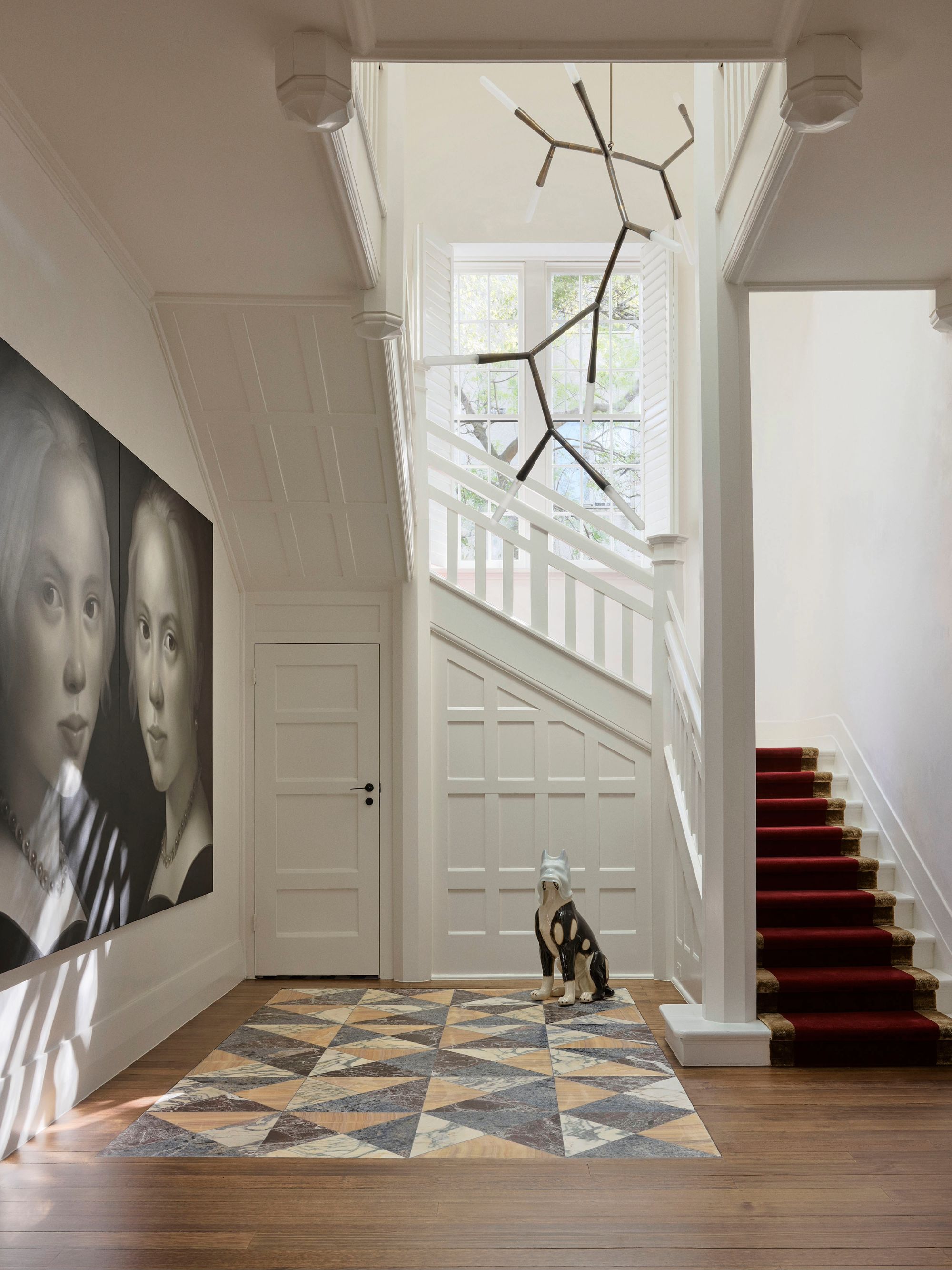 a grand entryway with a stone tiled floor and carpeted staircase