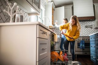 Two young girls unloading a dishwasher