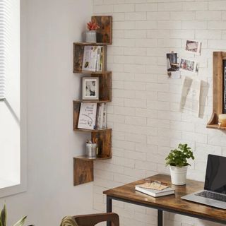 A wooden, wall-mounted bookshelf hung in a white room's corner