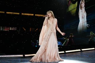 Taylor swift wears a cream alberta ferretti dress with lace detailing while performing onstage at the eras tour