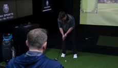 A golfer hits a putt, with a fitter looking over him