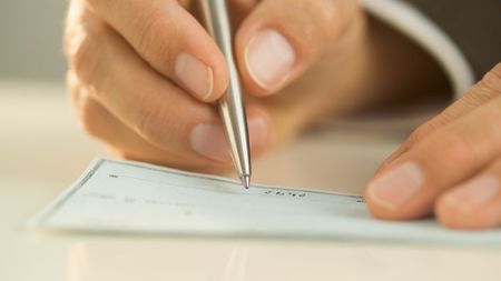 Close-up of a hand writing a check