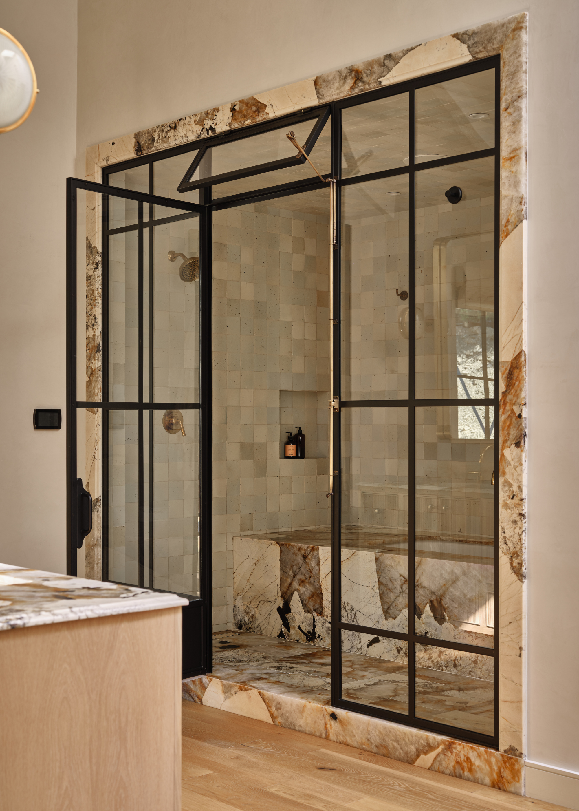 shower enclosure with marble bath and zellige tiles behind black crittal doors