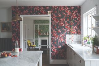 Brick colored printed wallpaper in a white kitchen with marble tops and metro tiling