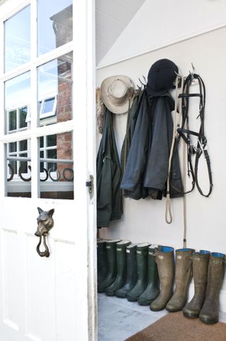 boot room and riding tackle in front porch of country house