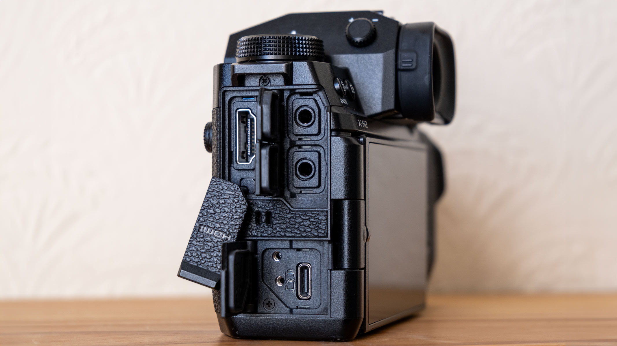 The Fujifilm X-H2 on a wooden shelf with USB-C port, mic jacks and HDMI port on display.