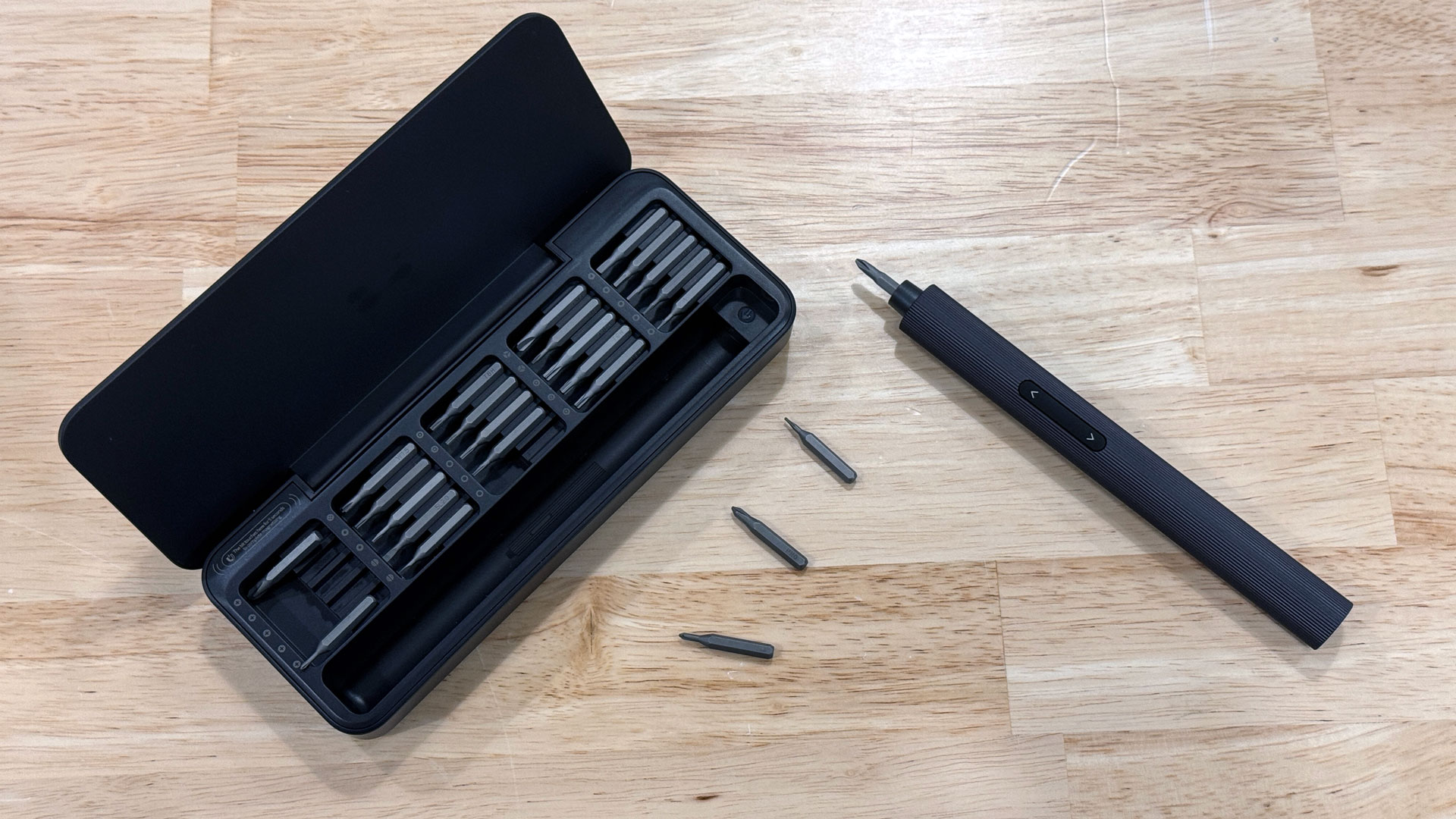 Hoto 25-in-1 screwdriver being used on a laptop on a wooden workbench.
