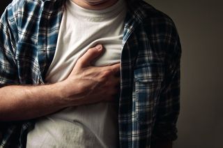 A man grips his chest in pain
