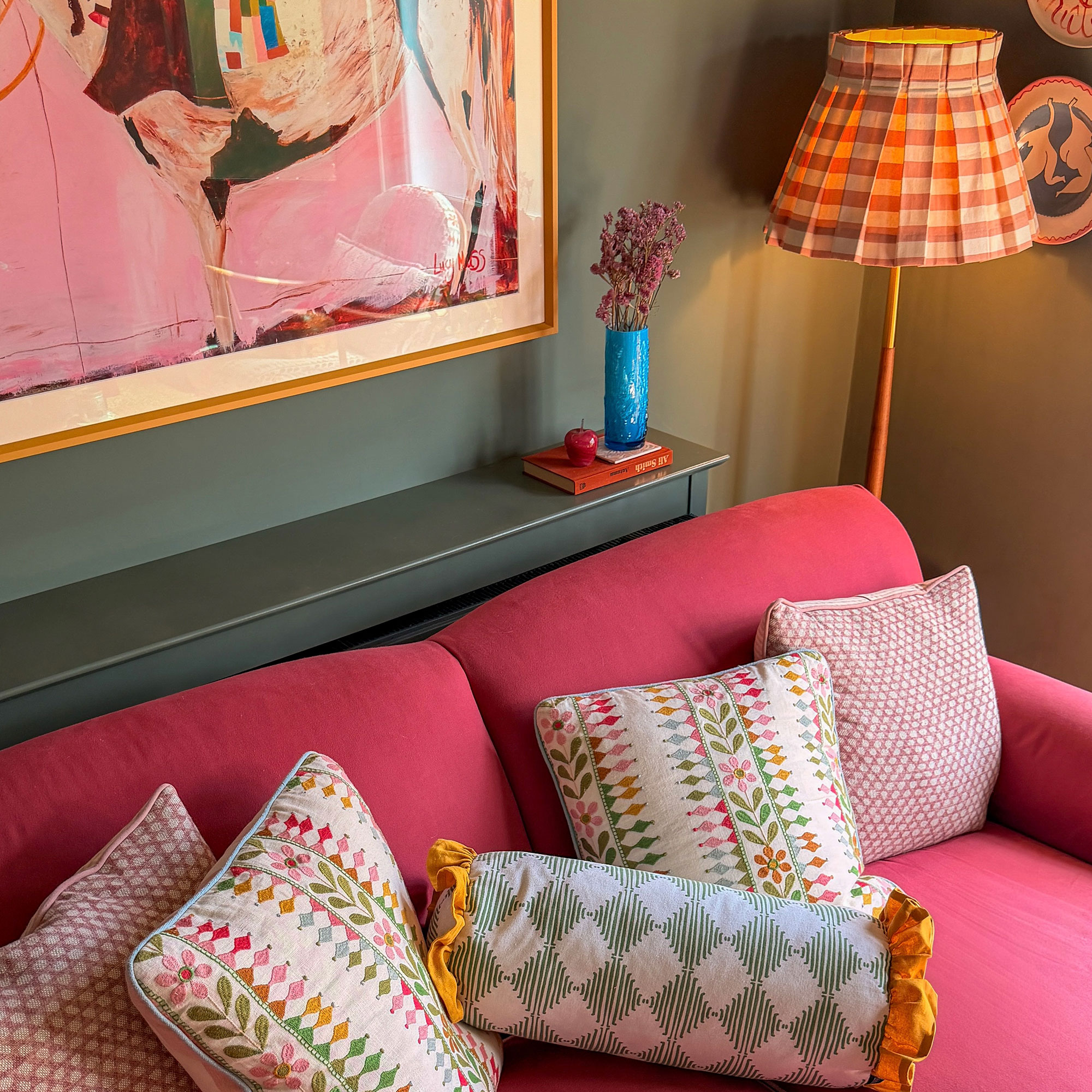 Pink sofa with patterned cushions against sage green wall