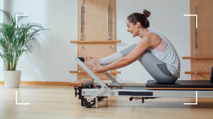 Woman on reformer Pilates machine in workout clothes laughing and smiling, representing what is reformer Pilates