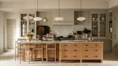A large family kitchen with pale green walls and cabinetry paired with a wooden island