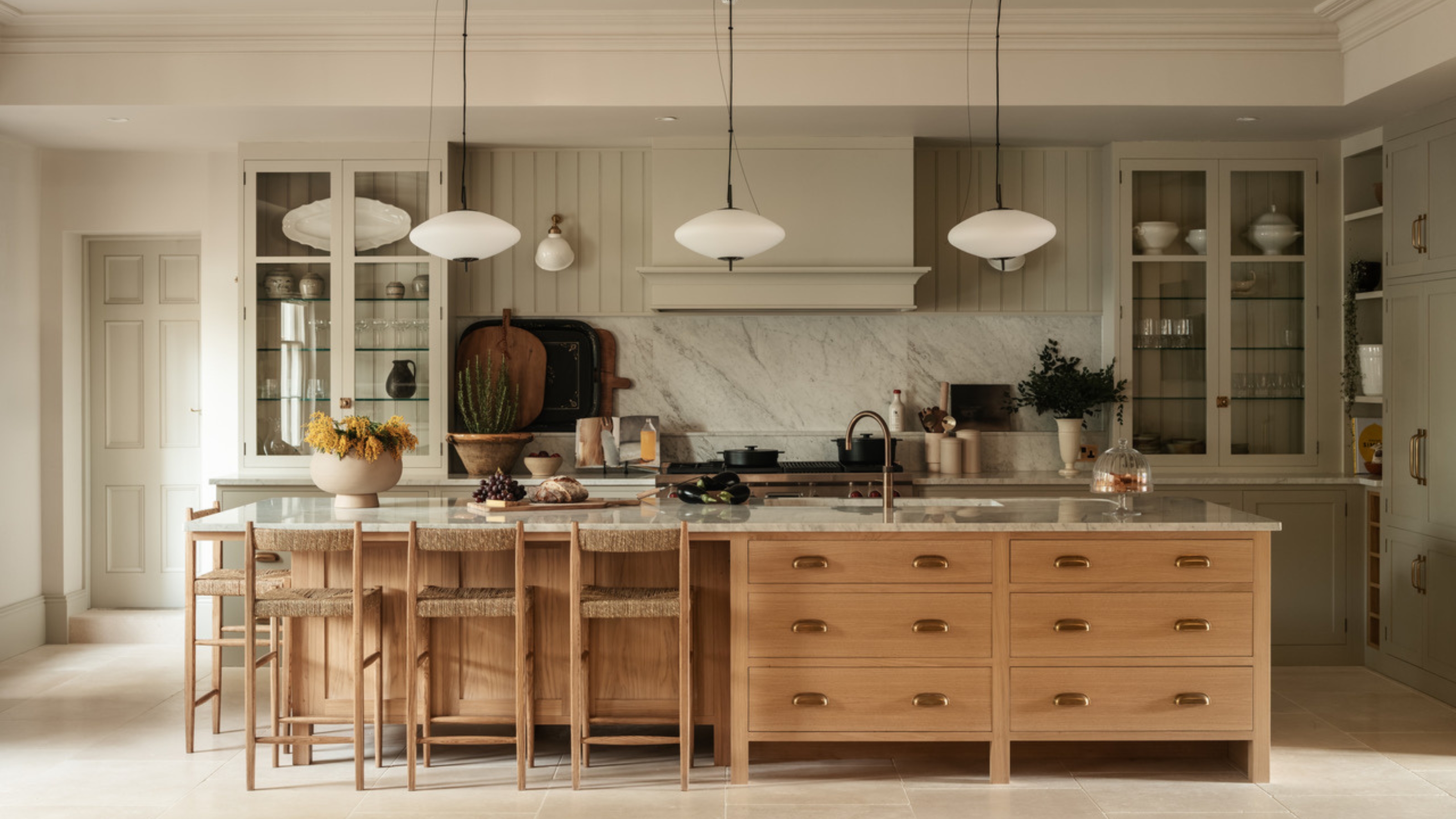 A large family kitchen with pale green walls and cabinetry paired with a wooden island