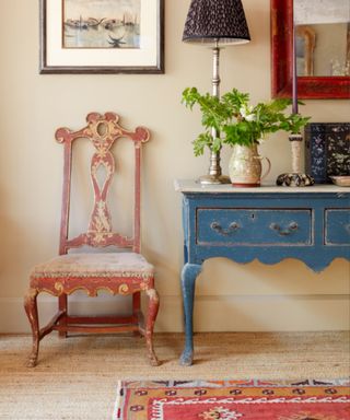 Vintage-style hallway with blue console table, antique chair, textured carpet and colorful rug