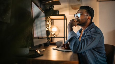 A thoughtful man in front of a computer screen in a home office