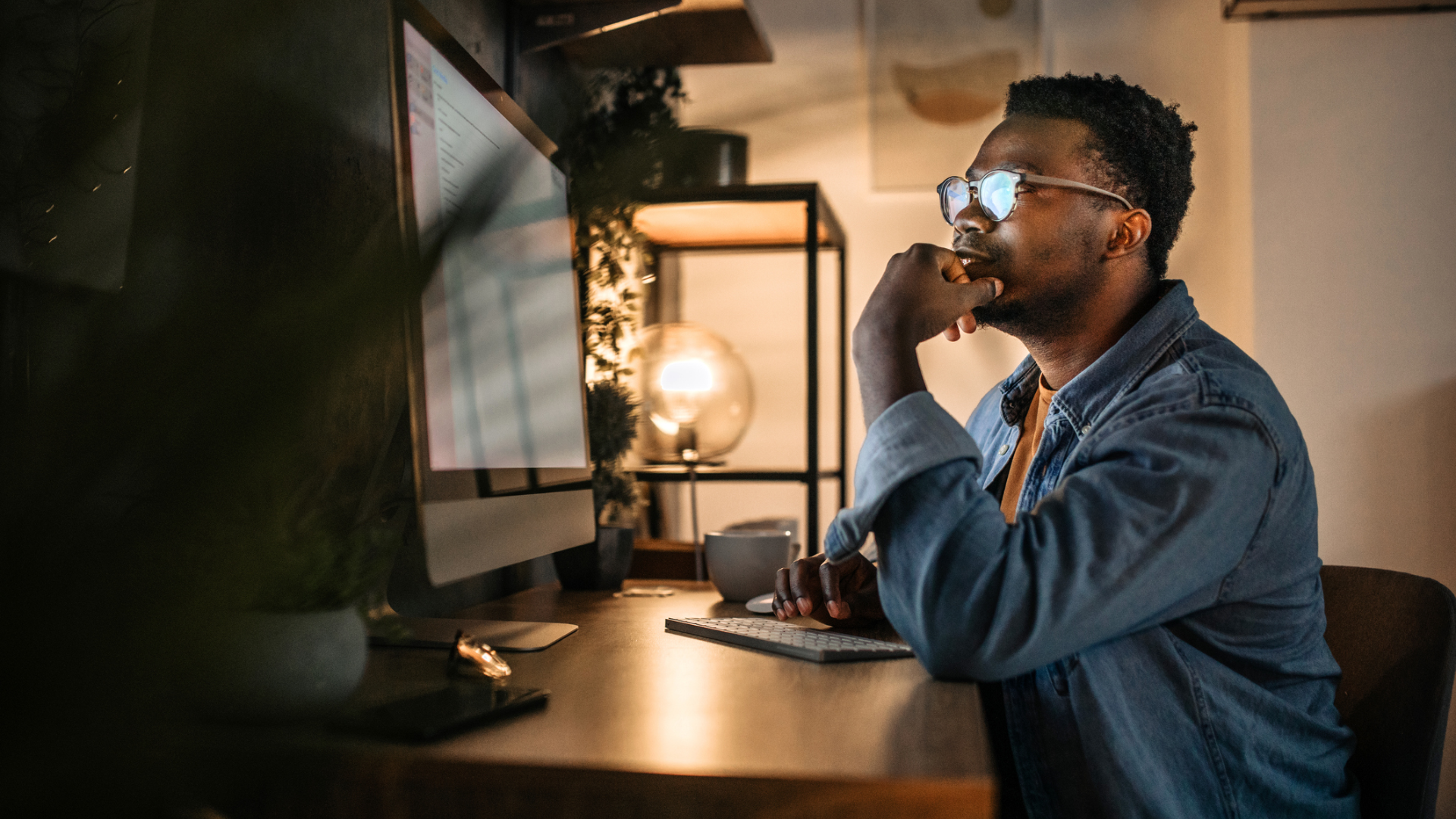 A thoughtful man in front of a computer screen in a home office