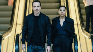 L-R Michael Fassbender as Martian and Ambreen Razia as Blair in The Agency, episode 5, season 2, streaming on Paramount+ 2026