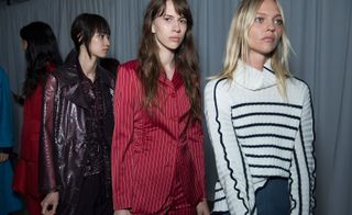 Models wear striped red suit, black and white knit and purple crocodile patterned trench coat