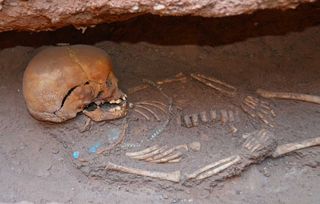 People were buried beside the pyramids in tomb chambers that often held more than one individual. This image shows a child who was buried with necklaces.