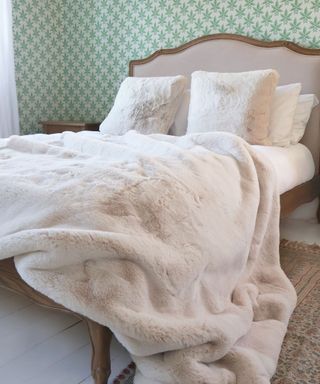 A green bedroom with a beige bed with fluffy pillows and throw pillows