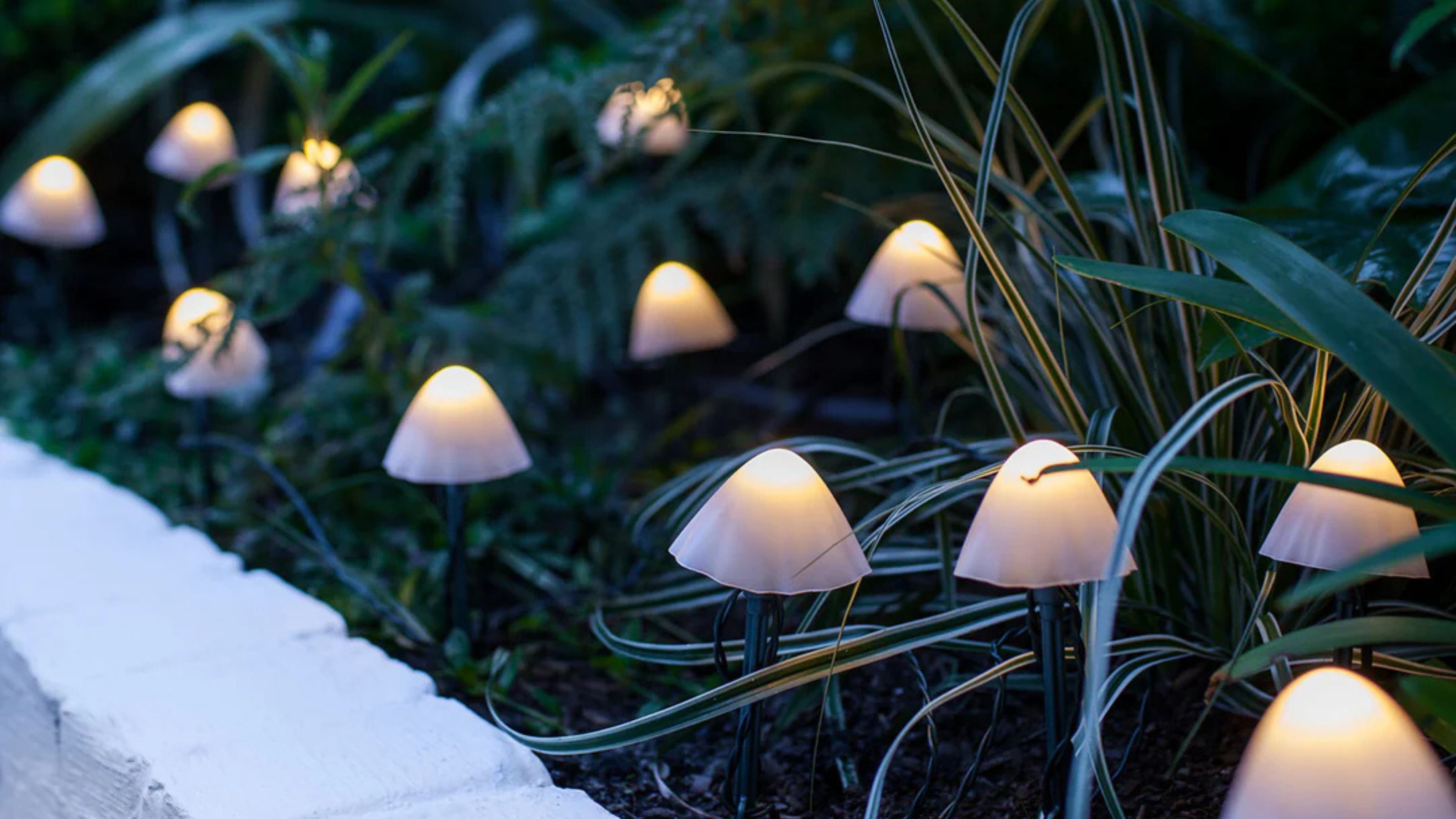 garden bed filled with plants and mushroom-shaped outdoor lights