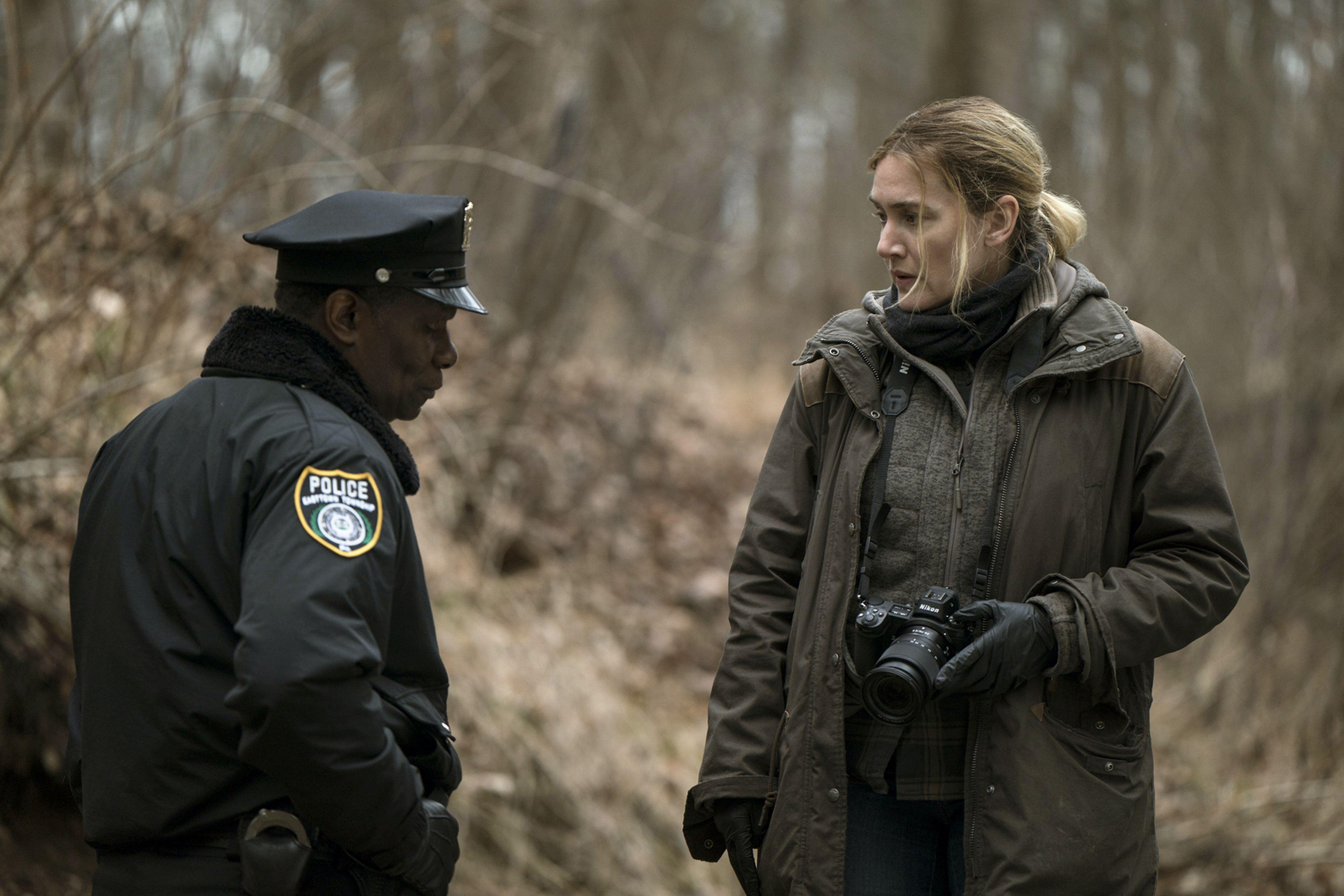 Kate Winslet stars in &#039;Mare of Easttown&#039; as a cop wearing a coat and gloves taking photos in the woods along with another detective