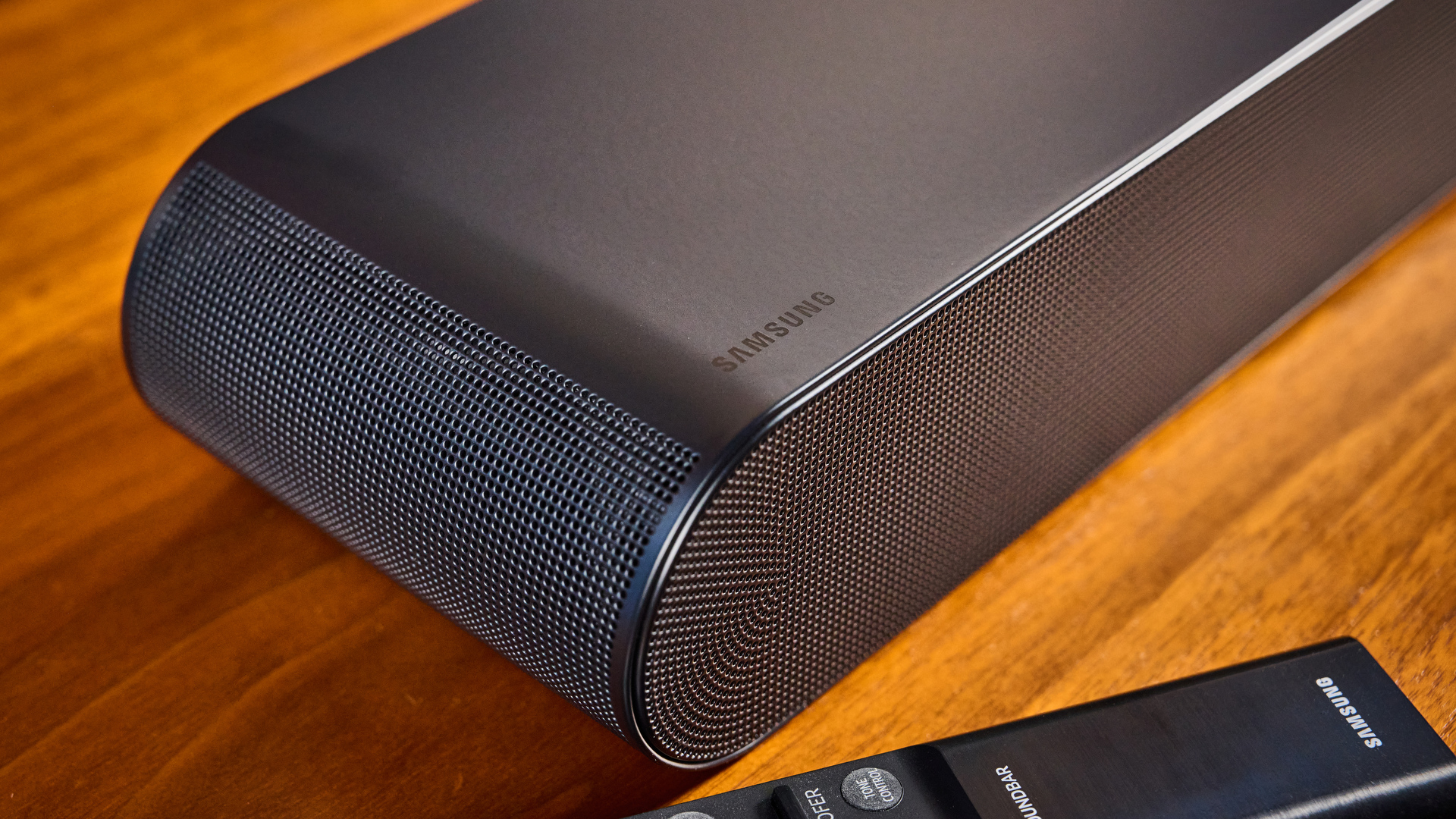 the samsung hw-s60D soundbar photographed on a wooden coffee table with a panasonic tv and a samsung soundbar against a blue background