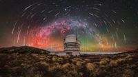 Observatory under a meteor shower with a colorful Milky Way arching across a starry night sky
