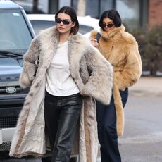 Kendall Jenner and Kylie Jenner wearing matching fur coats while walking in Aspen