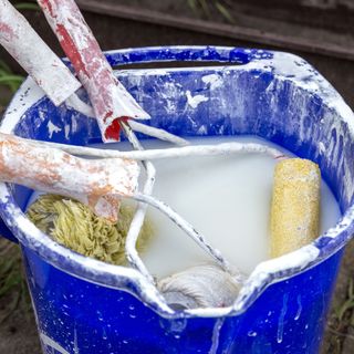 Dirty paint roller brushes in a bucket