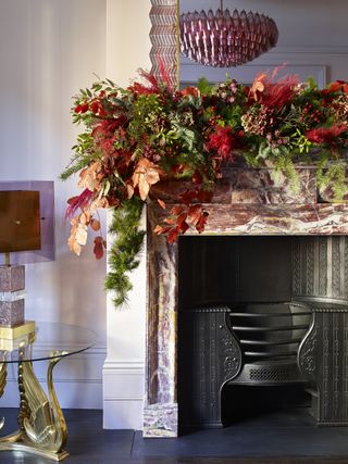 A fireplace decorated with a green and pink Christmas garland to match a pink stone fire surround