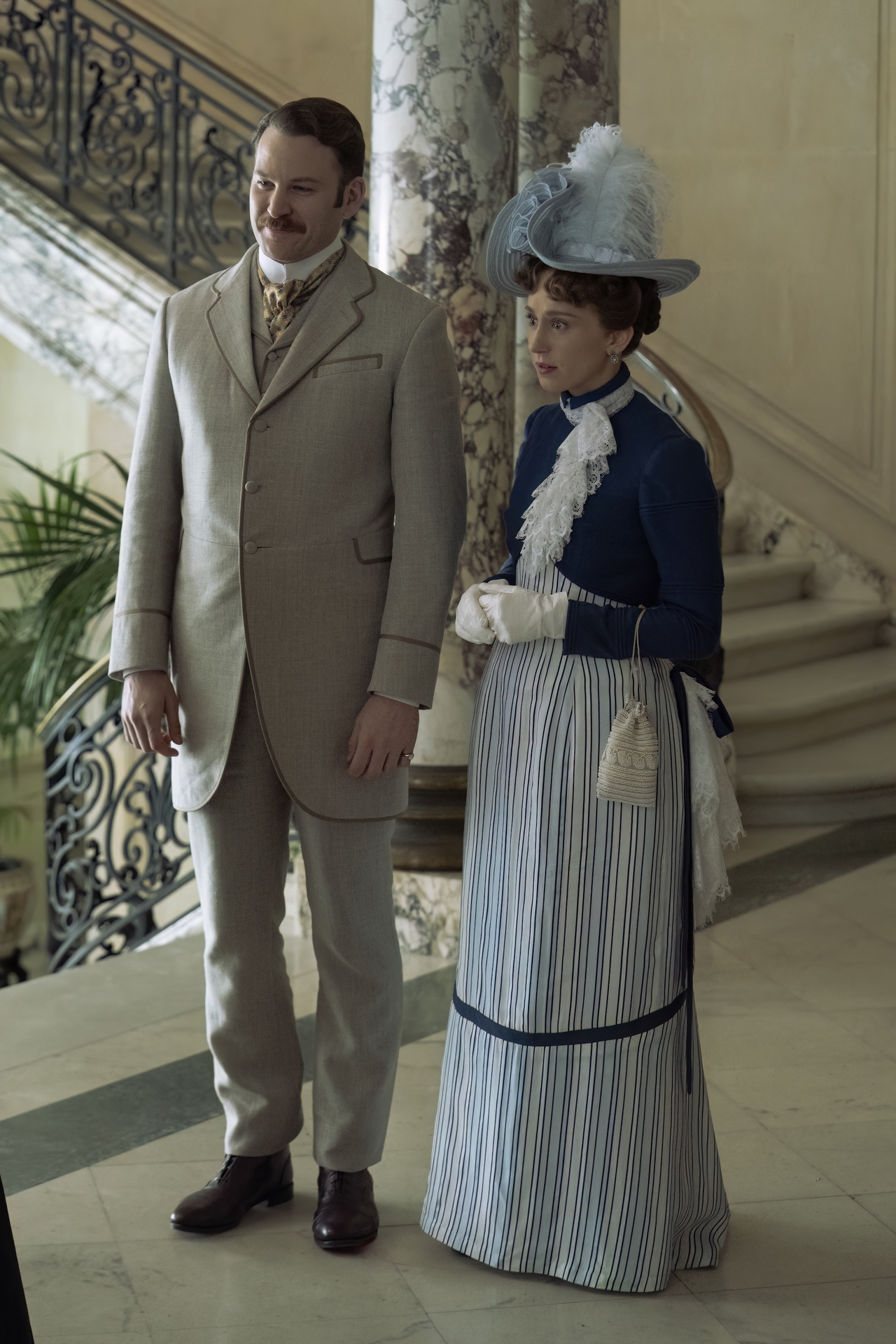 ben lamb and taissa farmiga as Hector and gladys wearing a tan suita nd a blue dress in the season 3 finale of the gilded age