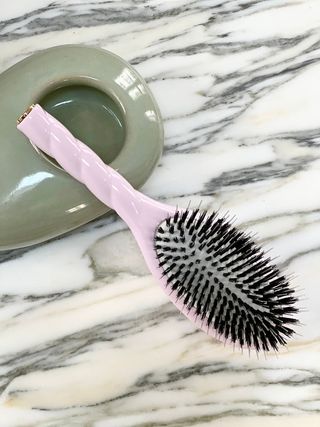 A pink hairbrush on a marble surface