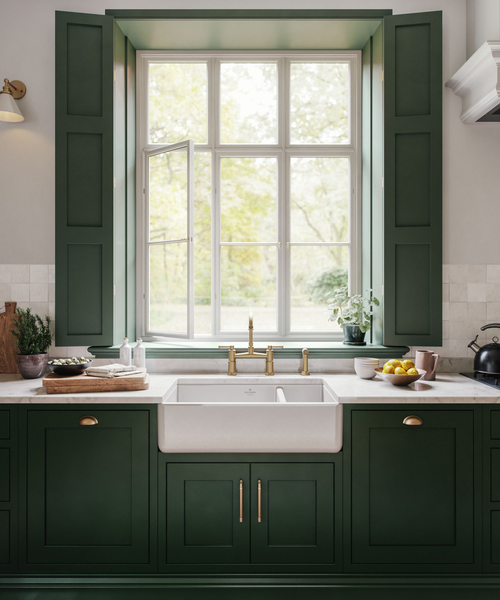 A white kitchen sink with gold faucets, green cabinets and green shutters, with a bright and sunny open window.