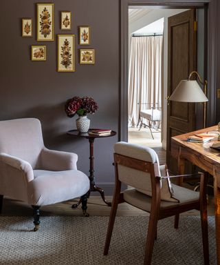 colors that go with brown, home office with brown walls, pale pink velvet armchair, gold framed artwork, antique side table, writing desk and chair, rug, view into bedroom