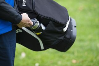 A golfer taking a flask of water out of their golf bag