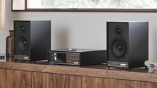 Ruark R610 and speakers in dark wood on a wooden shelf in a minimalist room