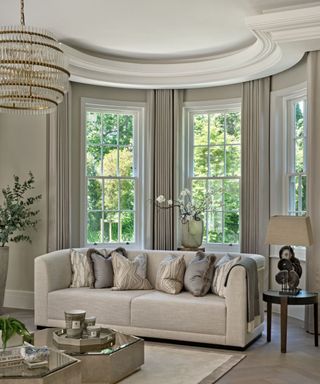 neutral living room with traditional architectural details, large bay windows and beige sofa