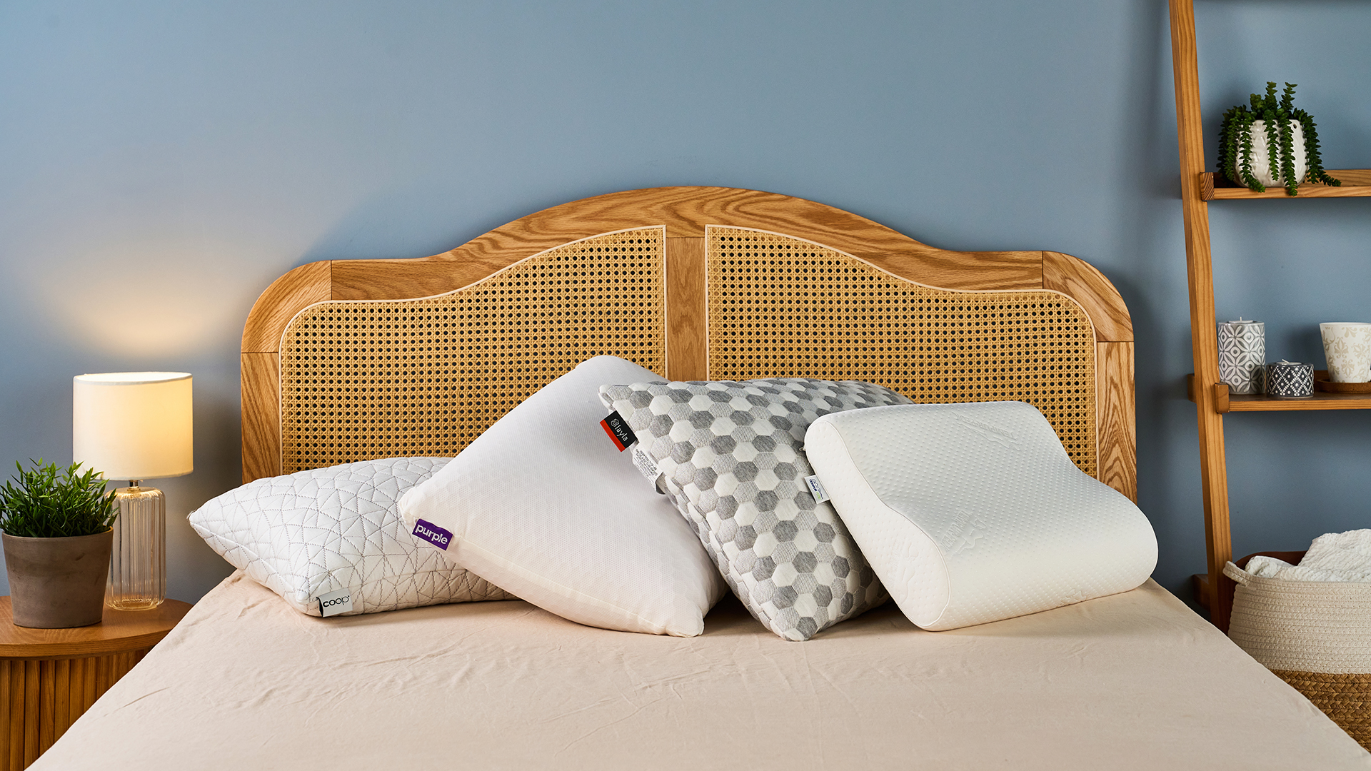 A stack of four pillows resting against each other at the head of a bed in a warmly lit room