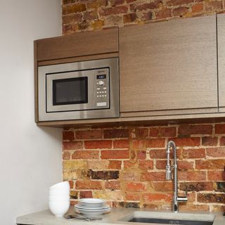 A kitchen with an exposed brick wall