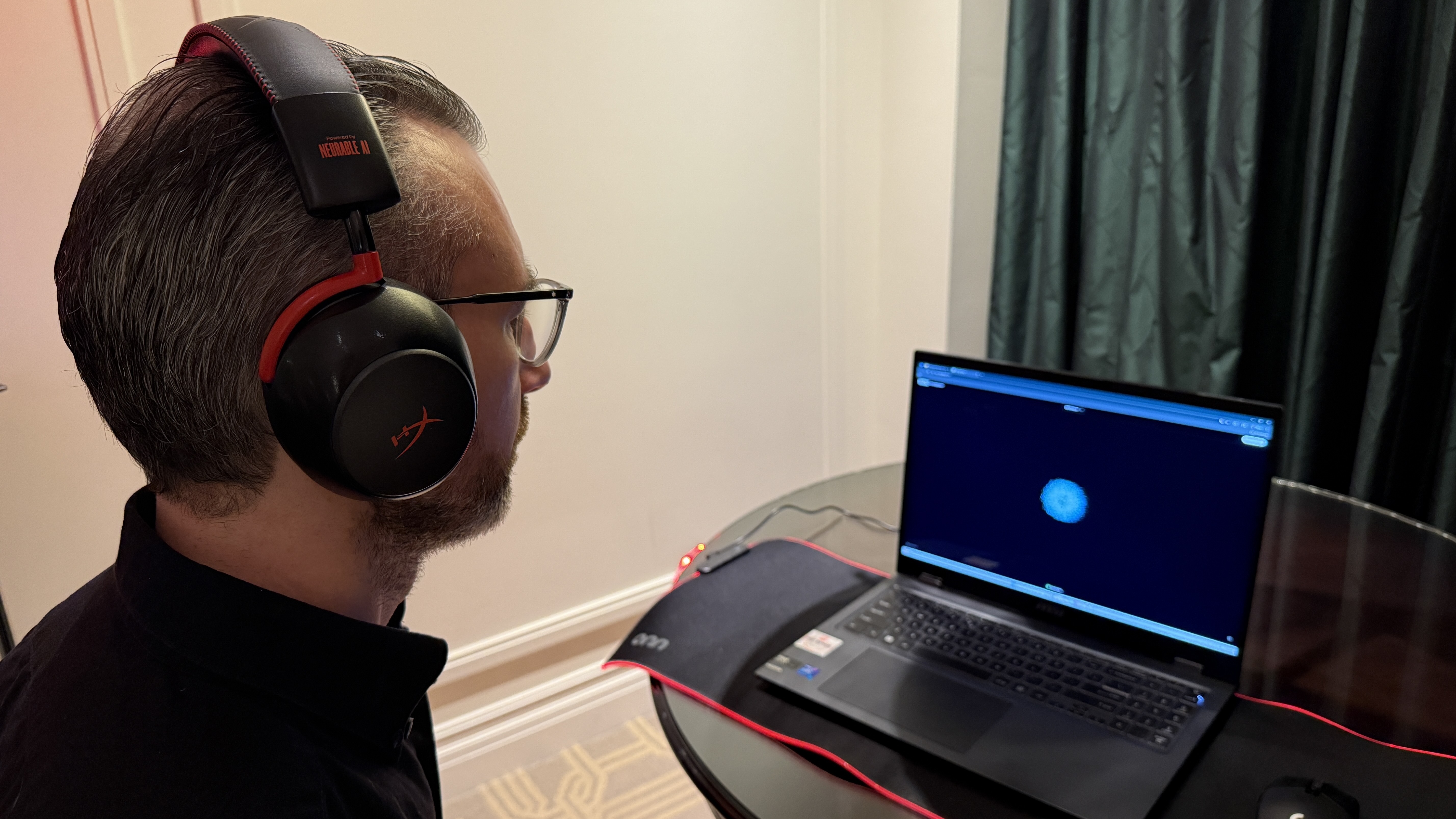 The HyperX Neurable prototype worn by a man, who is looking at a laptop with a small dot on it