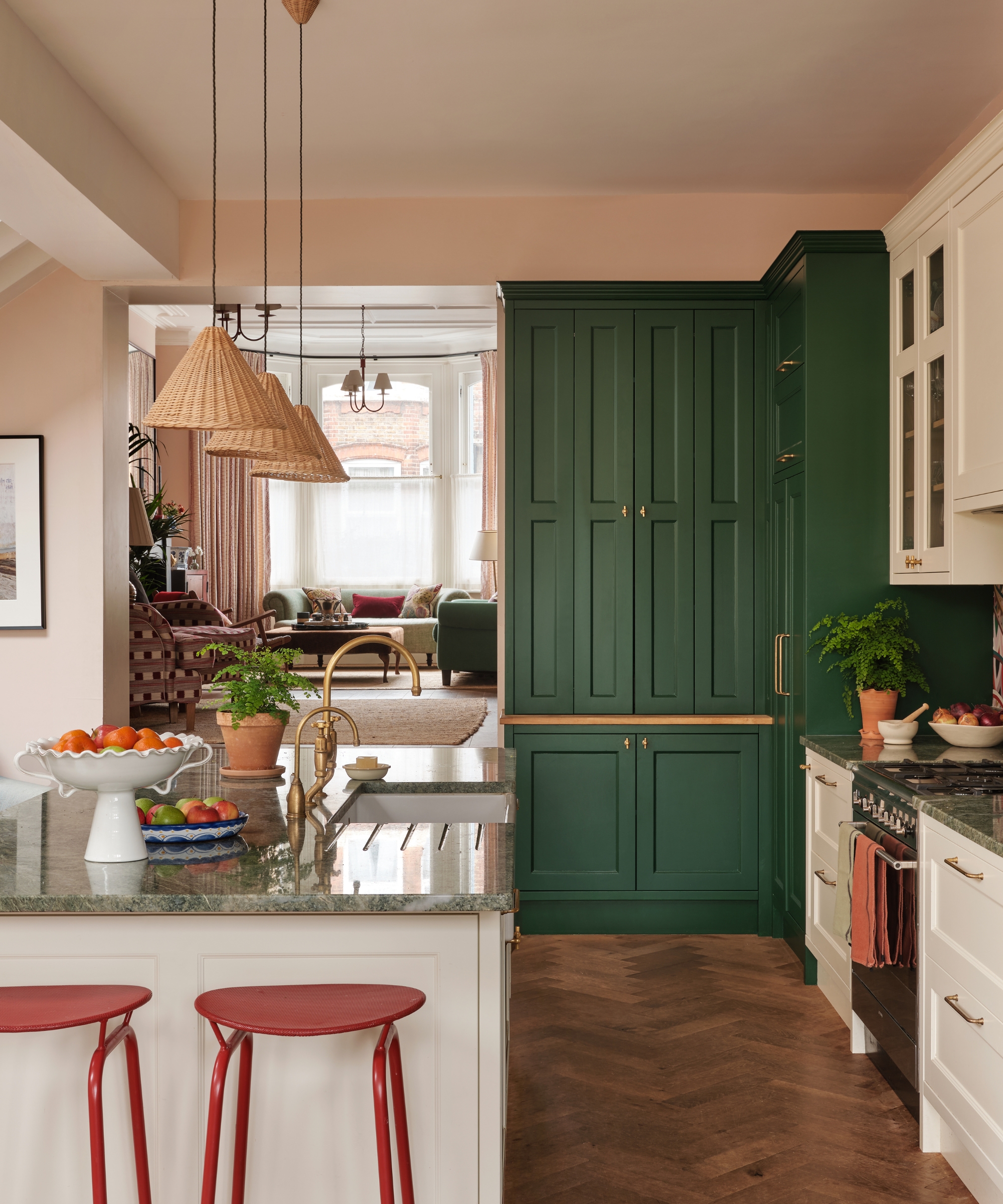 A lived-in kitchen with pink walls, white and green cabinets, a white island, and green countertops