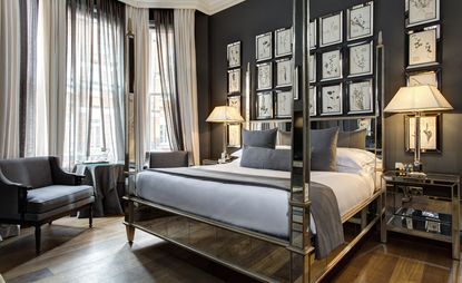 Bedroom in grey tones with a hardwood floor and mirrored four-poster bed