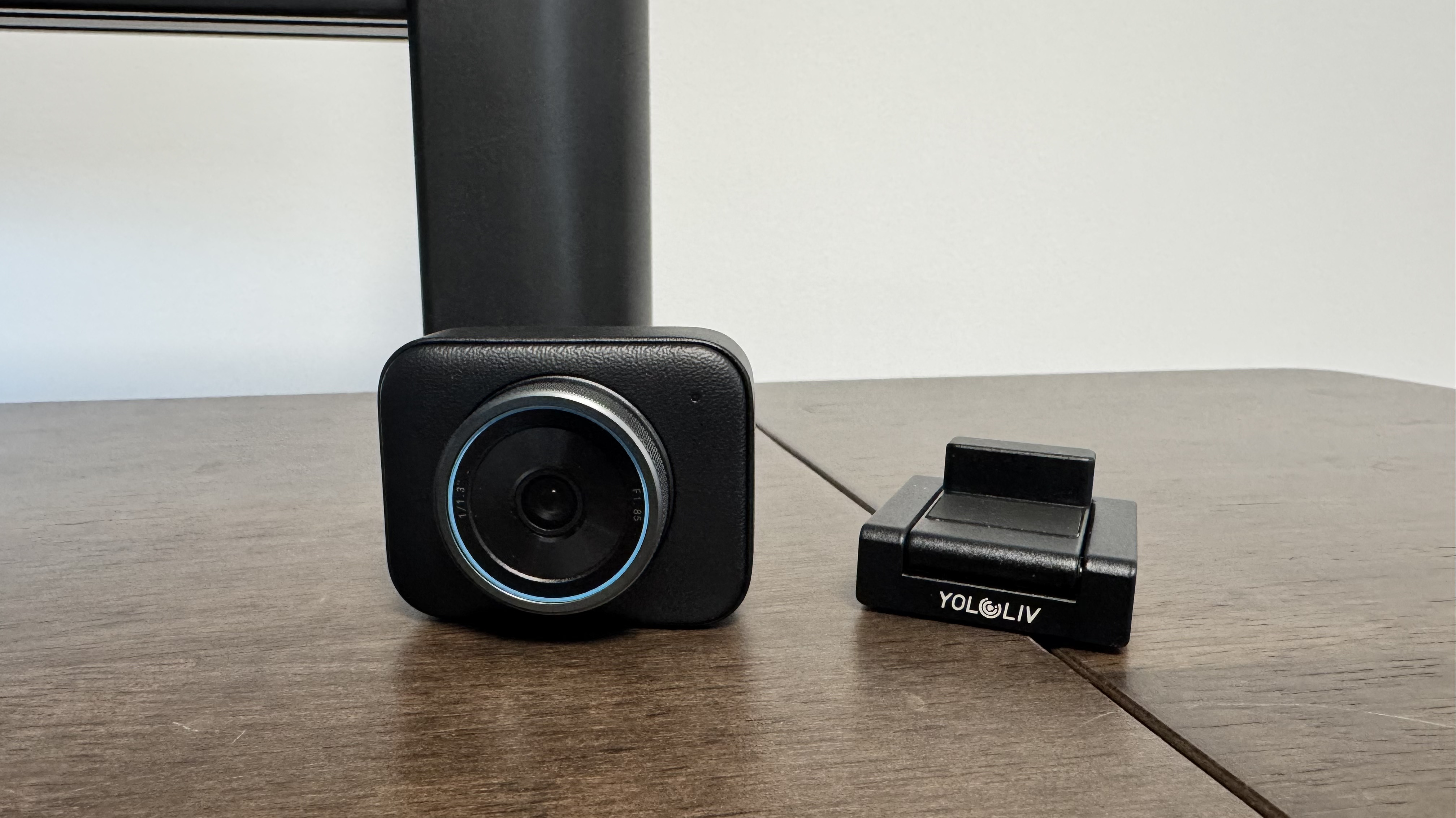 The Yololiv YoloCam S3 4K webcam from the front, next to its stand, on a wooden table