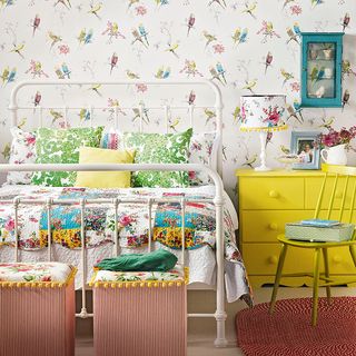 bird print wallpaper white iron bed floral bed linen and yellow chest of drawers