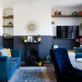 navy and white living room with navy sofa and armchair, dining table, shelving and wall mounted tv