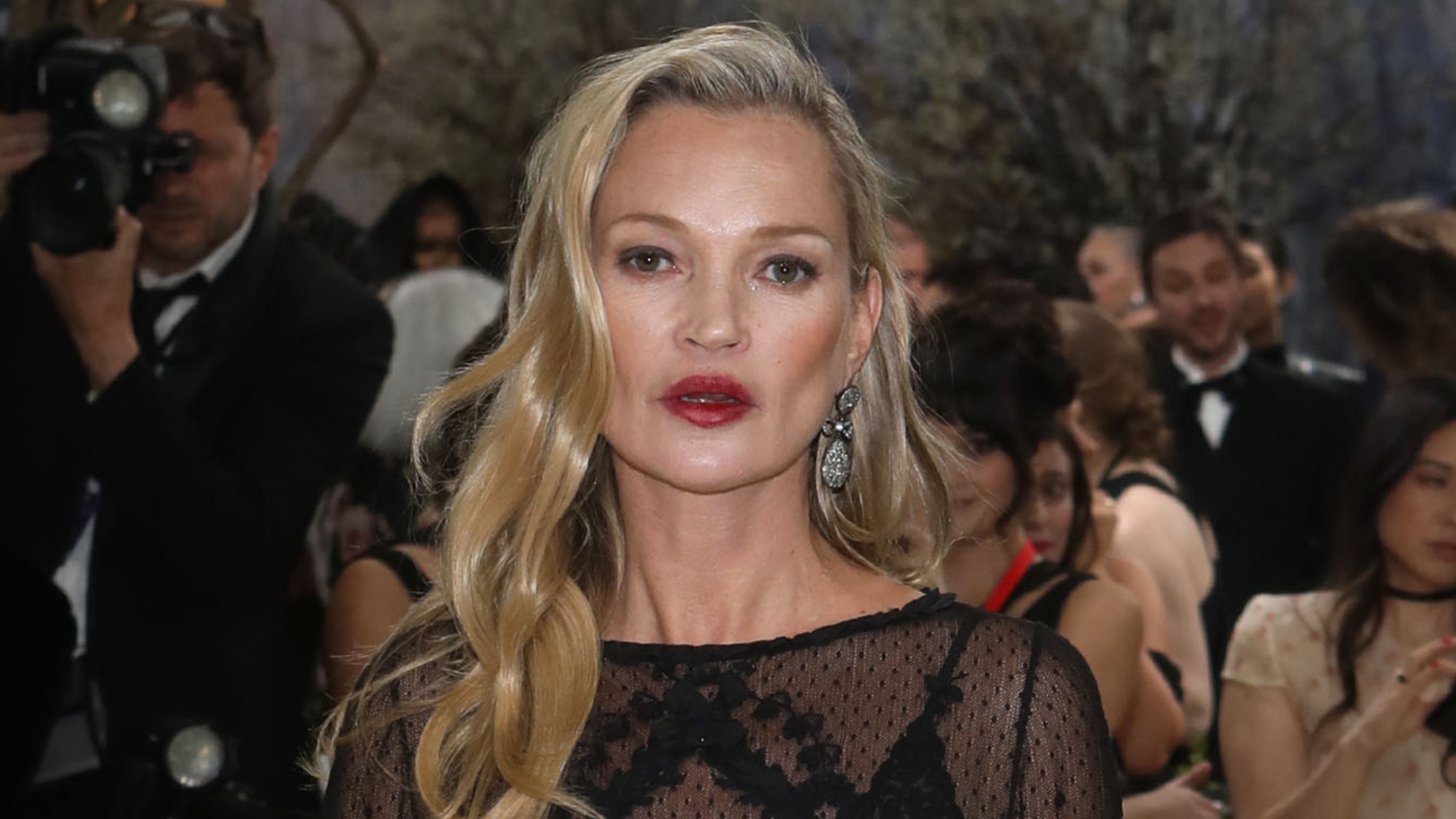 Image of Kate Moss with curled blonde hair tucked behind one shoulder, wearing red lipstick and black lace 
