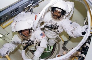 Astronauts Bernard A. Harris Jr., STS-63 payload commander, (top right) and C. Michael Foale, mission specialist, exit the airlock for their spacewalk on Feb. 9, 1995. 
