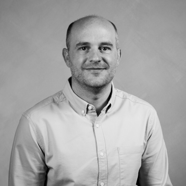 black and white headshot of male wearing shirt and smiling at camera