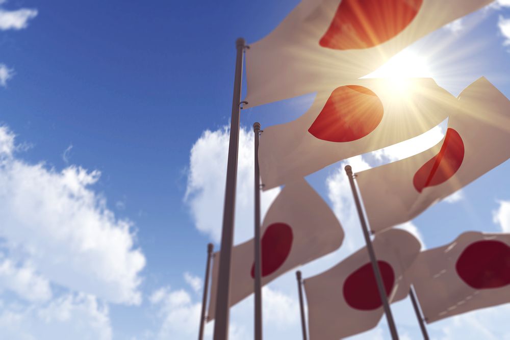 Japanese flags in front of a blue cloudy sky